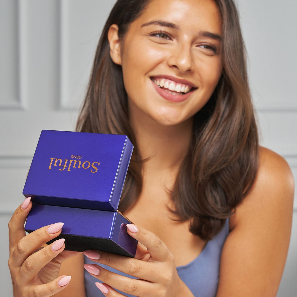 Woman holding a blue jewelry box with 'Soulful Gems' branding